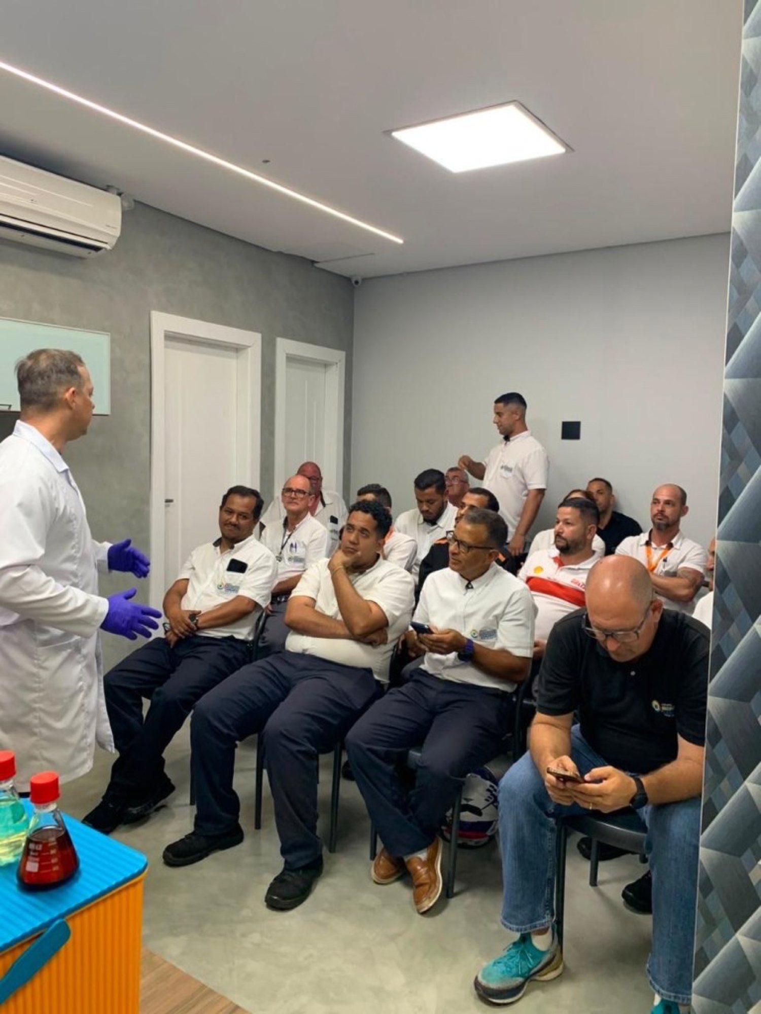 Instrutor em aula prática com equipe de posto em sala de capacitação